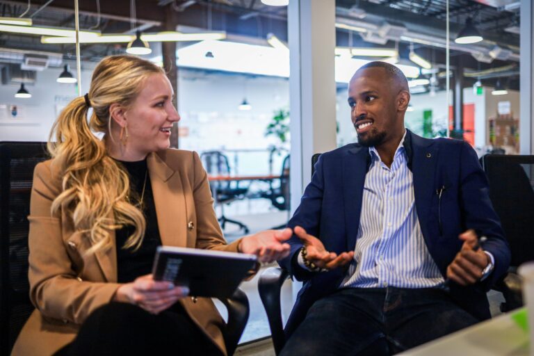 Two people sitting at a table talking to each other.