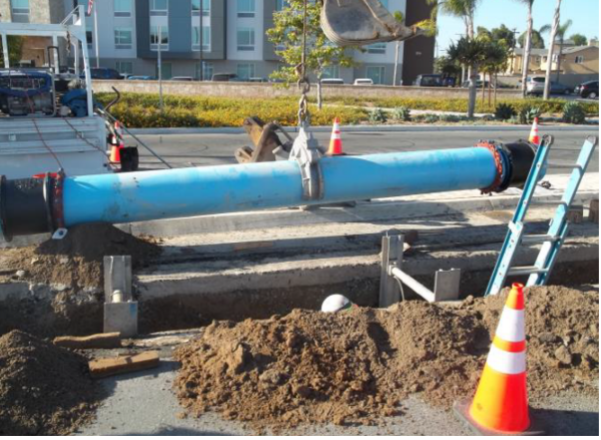 A pipe laying on the ground next to a street.