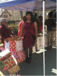 A woman standing next to some boxes of christmas presents.