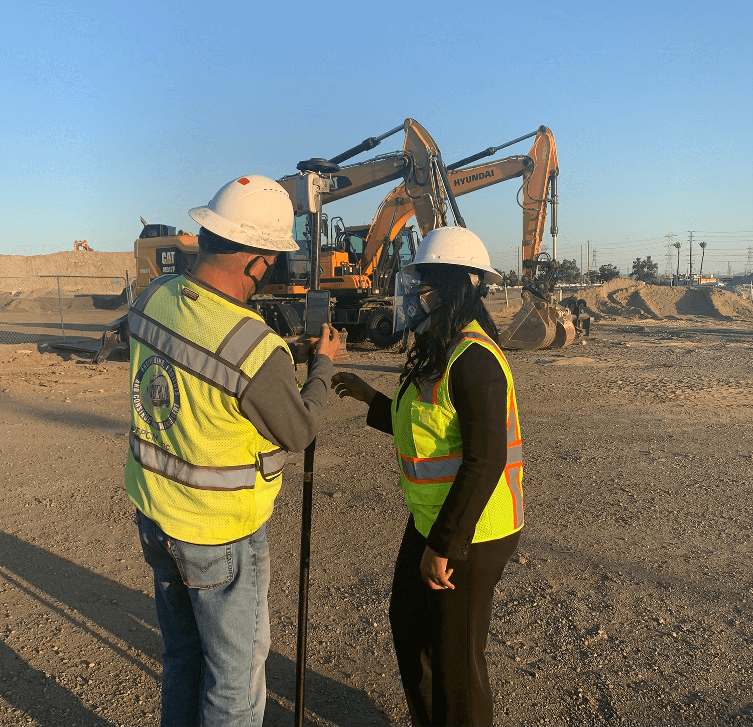 Two men in hard hats and safety vests talking.