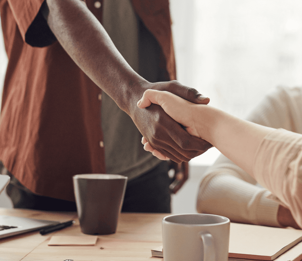 Two people shaking hands over a table.